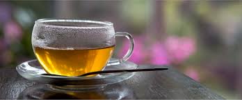 A clear glass cup of tea on a glass saucer.